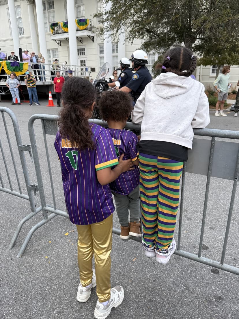 The kids in purple, green, and gold at a Mardi Gras parade
